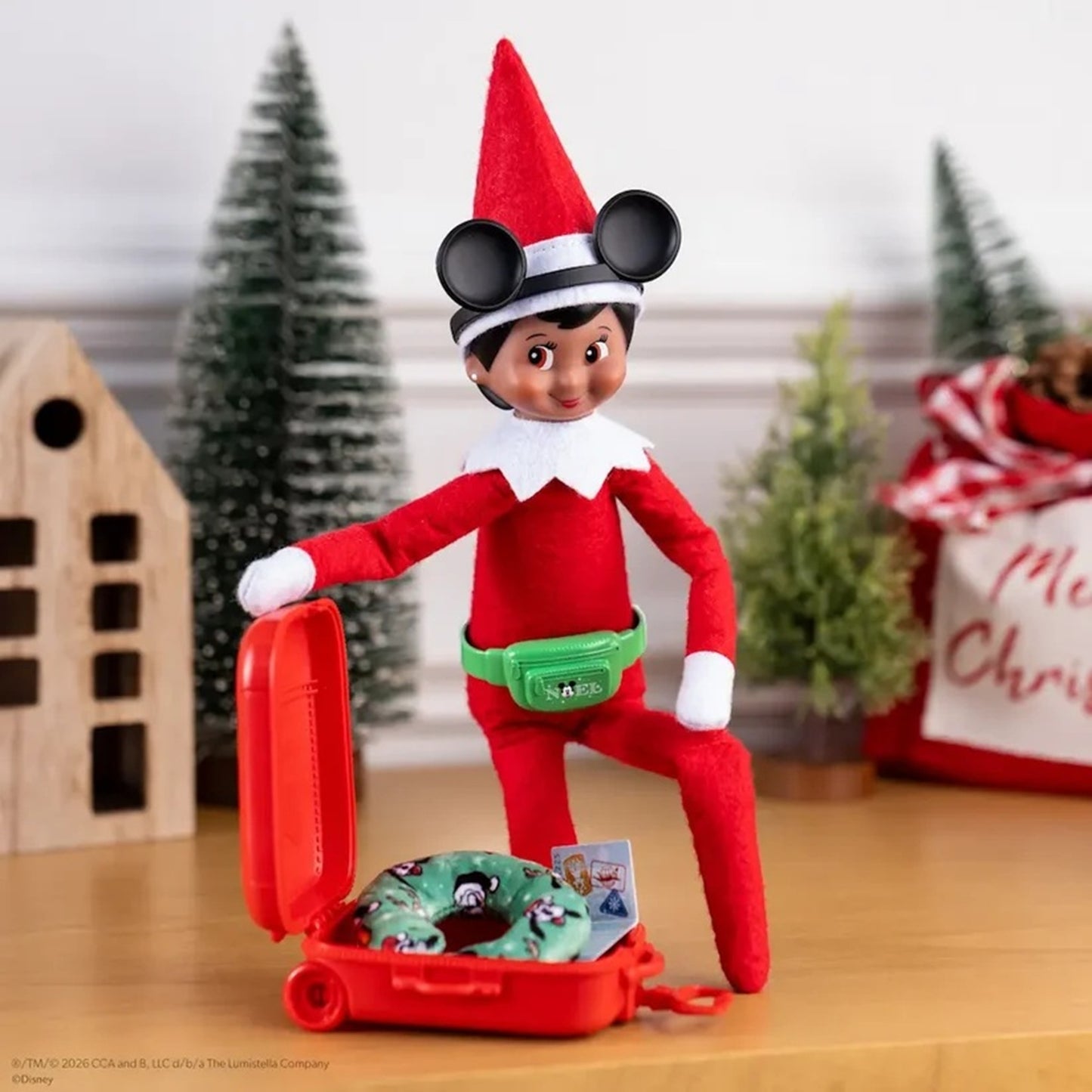 Elf on the Shelf with a suitcase and donut toy in a festive setting