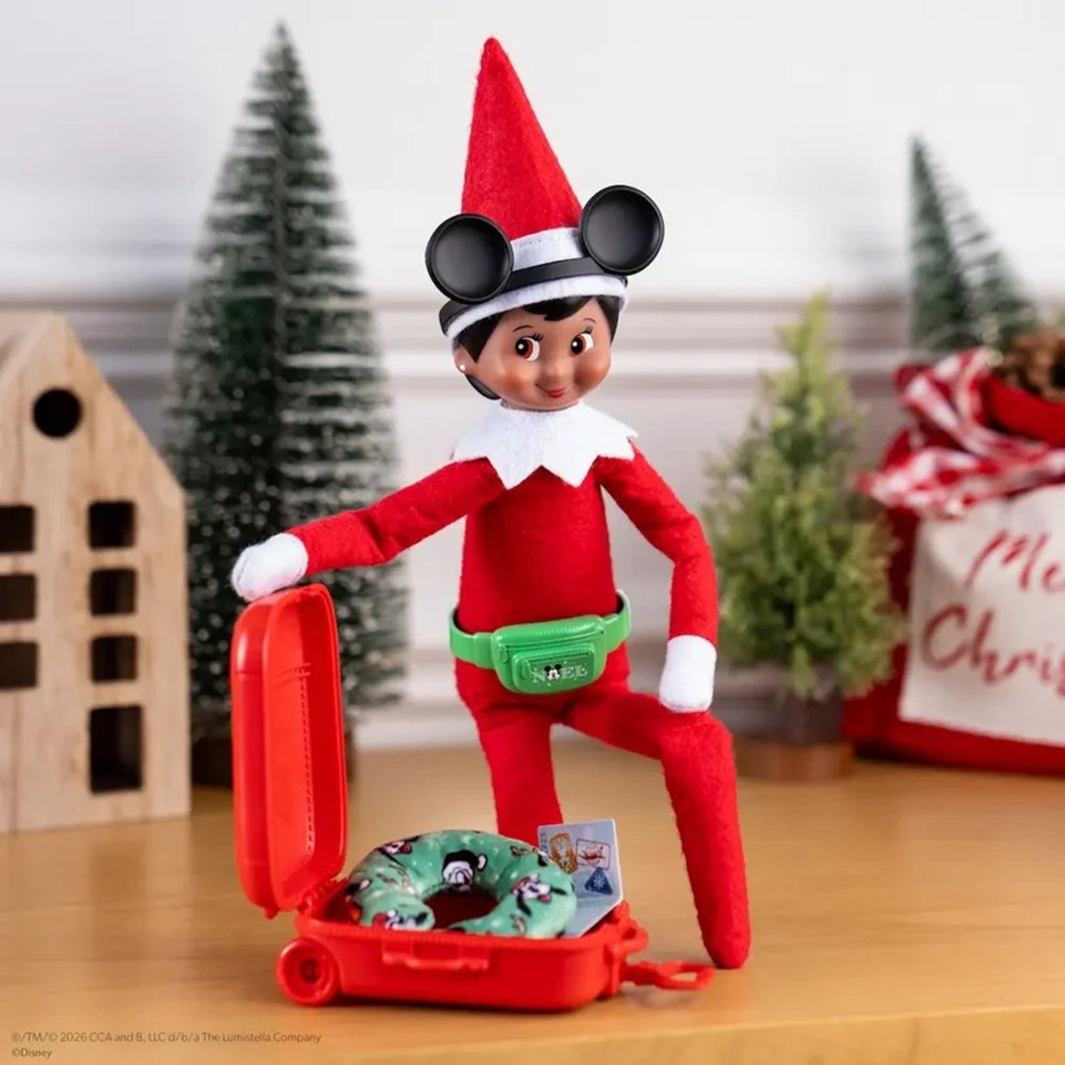 Elf on the Shelf with a suitcase and donut toy in a festive setting